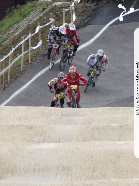 Coupe des Lacs 2009 de BMX, manche de Cran-Gevrier - le dim. 08.11.2009. 5e et avant-dernière manche de cette compétition franco-suisse de BMX. – Ça joue des coudes entre deux pilotes à la sortie du virage, mais pas de chute pour cette fois... – « Coupe des Lacs 2009 de BMX, manche de Cran-Gevrier » – 5e manche de la Coupe des Lacs sur la piste de bicross de Cran-Gevrier. – mots associés : bmx, coupe des lacs